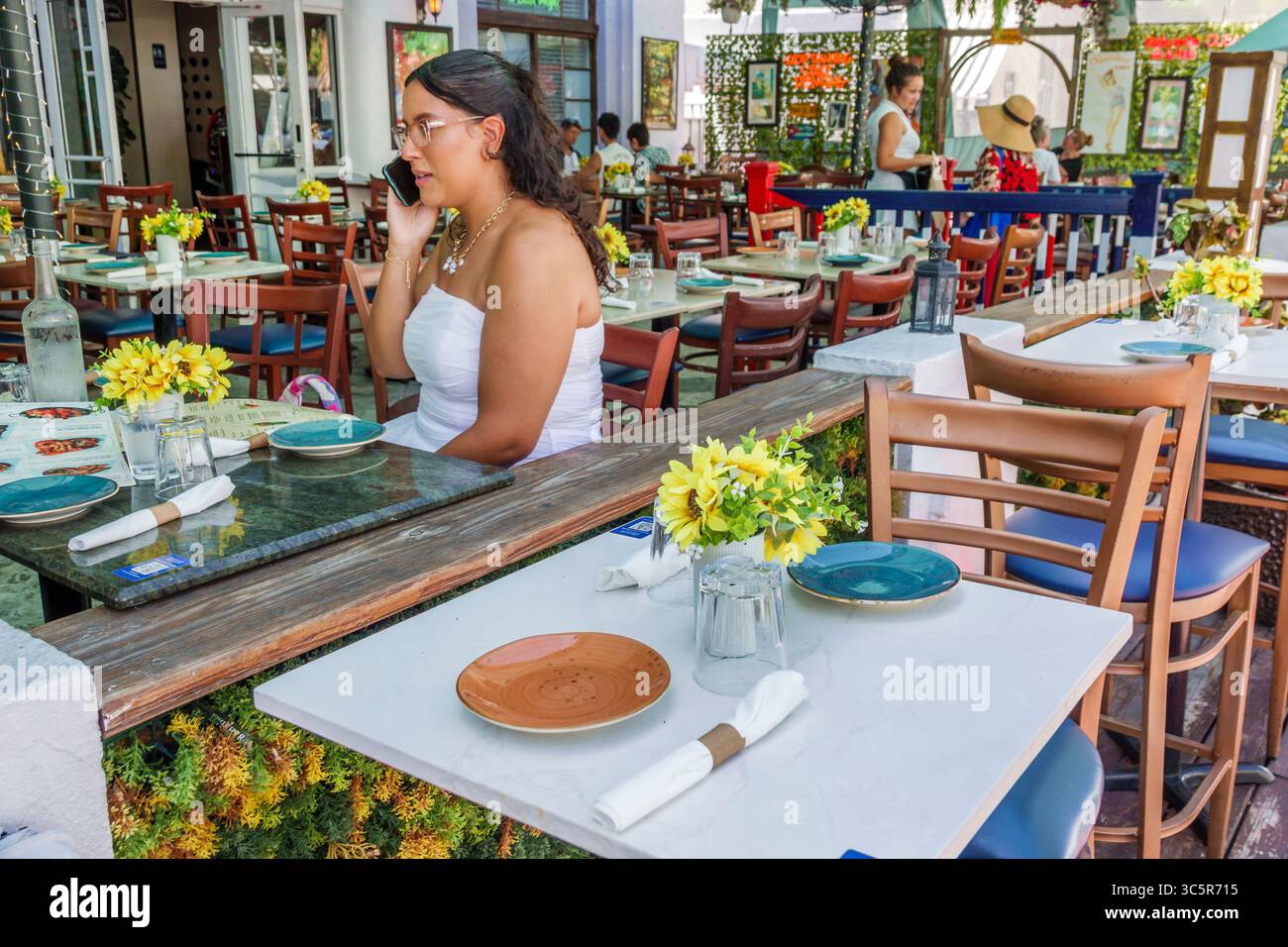 Miami Beach Florida,South Beach,Washington Avenue,Havana Vieja Cuban Restaurant,Hispanic young adult woman with glasses wearing white top sitting alon Stock Photo