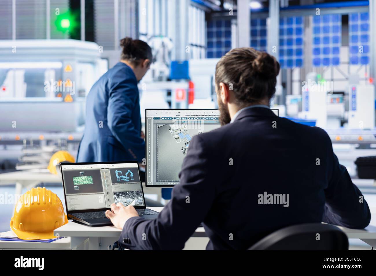 Photovoltaics factory worker at PC desk analyzing data, reviewing
