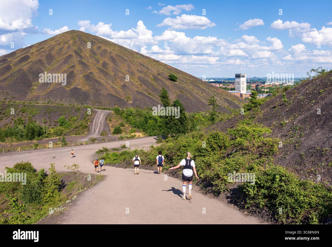 Tourists climb on foot the spoil heap 74A while local people go jogging on the sloping path with view on the spoil heap 74 in Loos-en-Gohelle, France Stock Photo