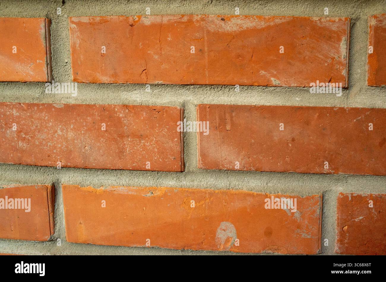 Brick wall with a few bricks missing. The wall is red and has a rough texture. The missing bricks give the wall a somewhat unfinished look Stock Photo