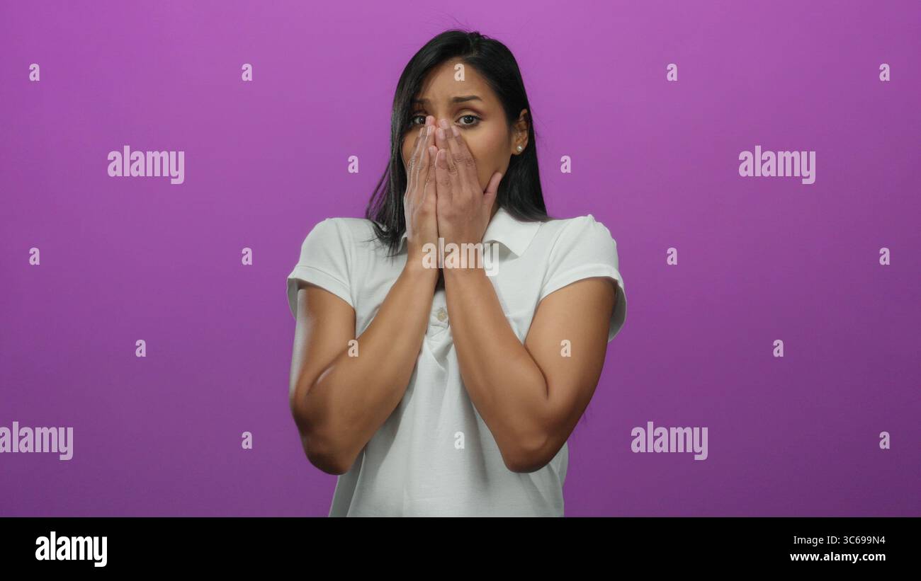 Woman expressing surprise against a vibrant pink background, showcasing emotions through various gestures while isolated in a studio setting. Stock Photo