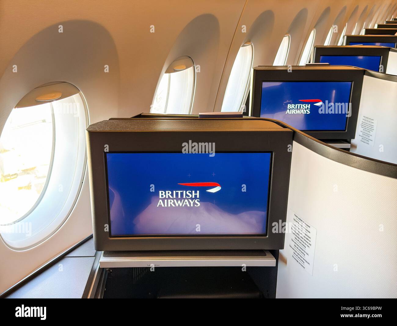 London, England, UK - 20 May 2025: Row of television screens in front of seats in the Club World business cabin of a British Airways jet - Smartphone Captured Stock Image