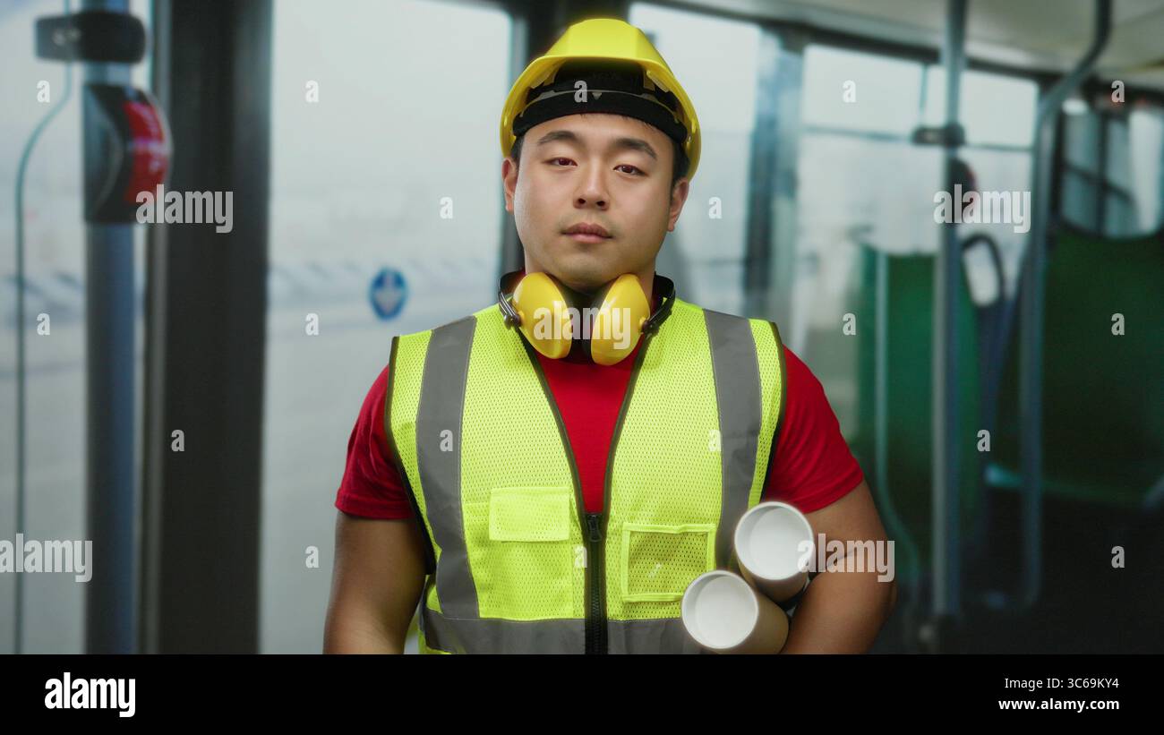 Planni Young asian man with blueprints wearing safety vest and hard hat ...