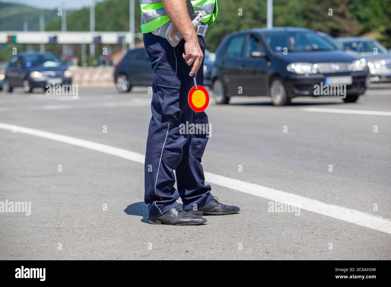 Policeman wearing a reflective vest conducts roadside inspections, managing vehicle flow and ensuring safety Stock Photo