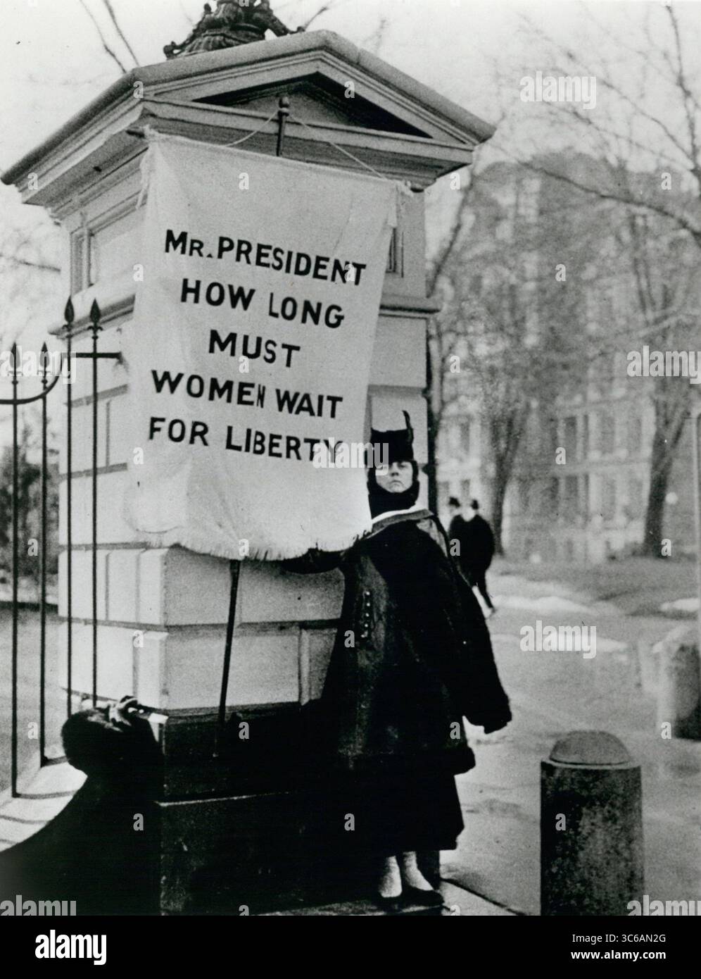 1917 - Washington, DC, USA - A flag-bearer for women's rights stands at a corner of the white house grounds asking ''Mr. President, how long must women wait for liberty''.  On June 4, 1919 women throughout the United States received the right to vote after the the 19th amendment was passed by congress and sent to states for ratification. Photograph by Harris & Ewing. (Credit Image: © Keystone Pictures USA/ZUMAPRESS.com) Stock Photo