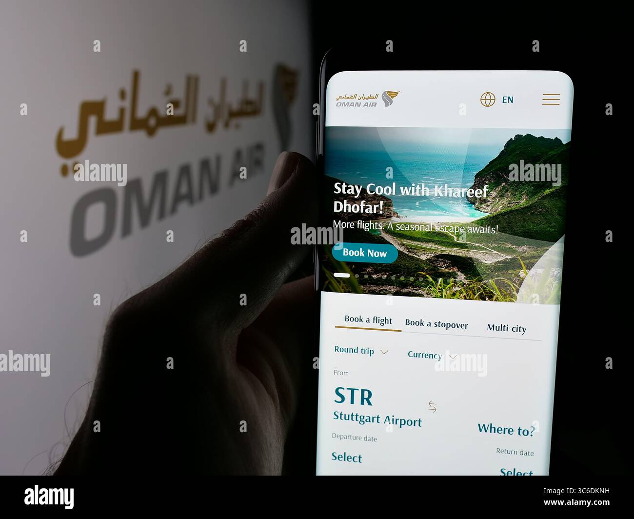 Stuttgart, Germany - 06-20-2025: Person holding cellphone with webpage of airline company Oman Air on screen in front of logo. Stock Photo