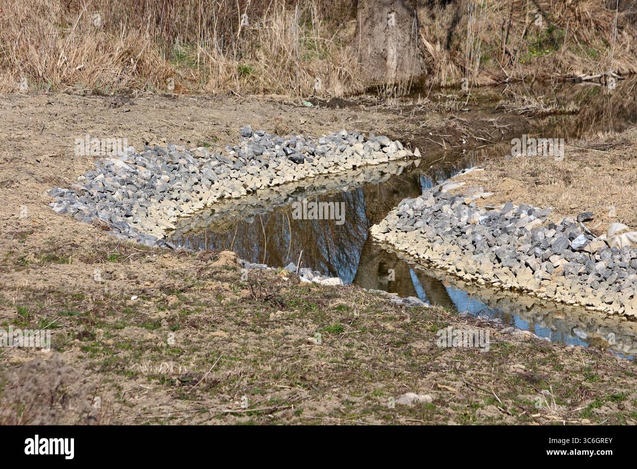 Shallow stream banks are reinforced with layers of angular riprap ...