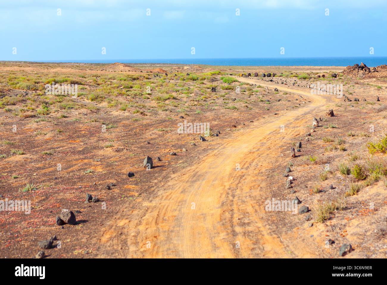 Dirt road winds through arid landscape, stretching towards a distant ...