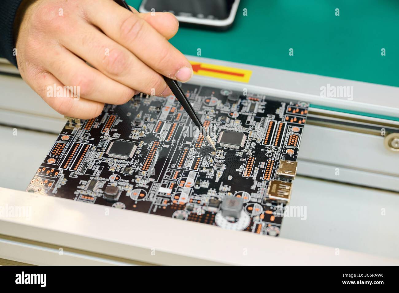 Technician working on a circuit board in a high-tech electronics lab during daytime Stock Photo