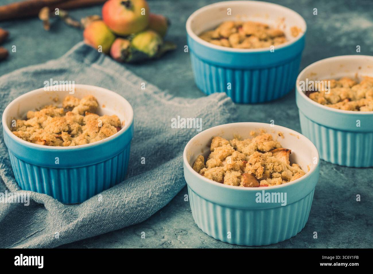 Apple crumble in small blue molds on a rustic gray table Stock Photo