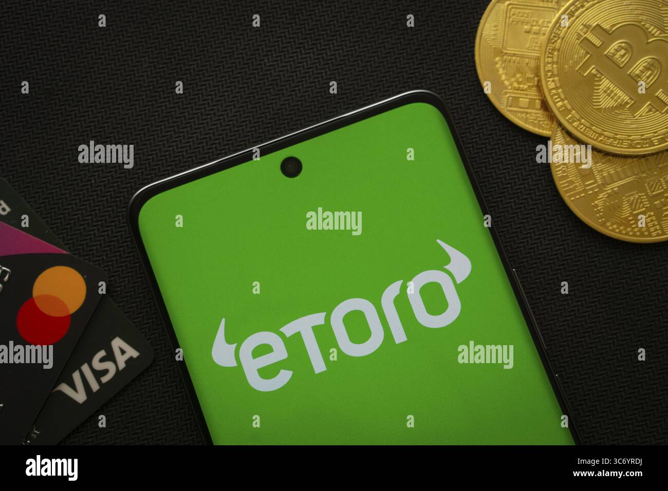 Smartphone with Etoro logo with Bitcoin coin on yellow background. Trading  platform, investing in stocks and cryptocurrencies Stock Photo - Alamy