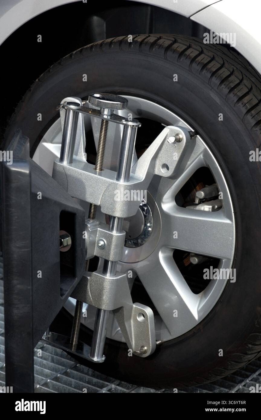 Car wheel fixed with computerized wheel alignment machine clamp. Closeup of repairshop equipment Stock Photo