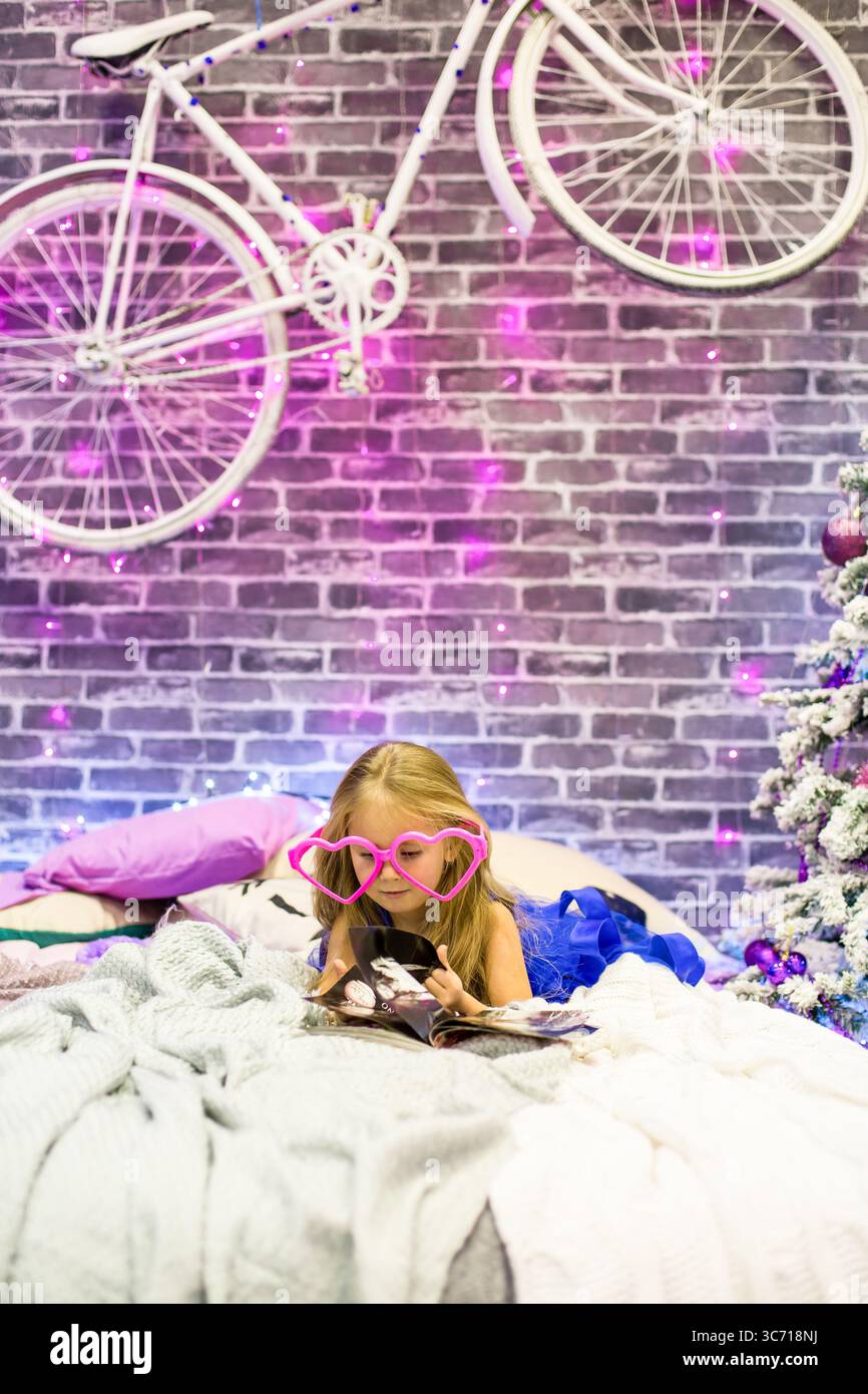 Pretty little girl 4 years old in a blue dress. Baby in Christmas room ...