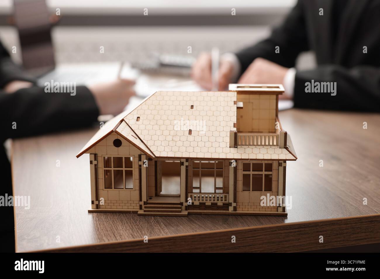 Real estate agent working with client at desk in office, focus on house model Stock Photo - Alamy