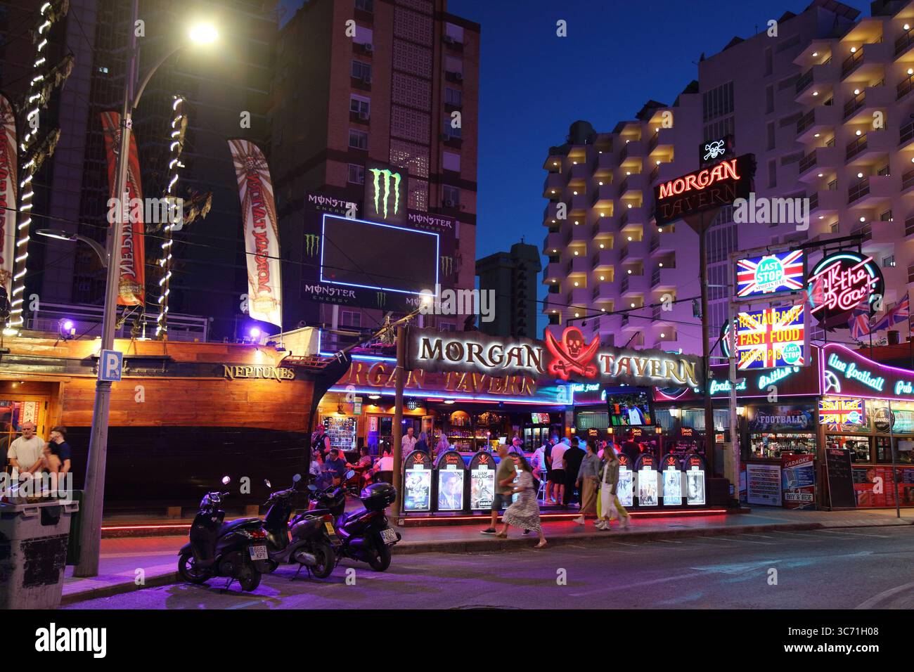 BENIDORM, SPAIN - APRIL 9, 2025: People visit Morgan Tavern restaurant illuminated with neons by night in Benidorm, Spain. Stock Photo