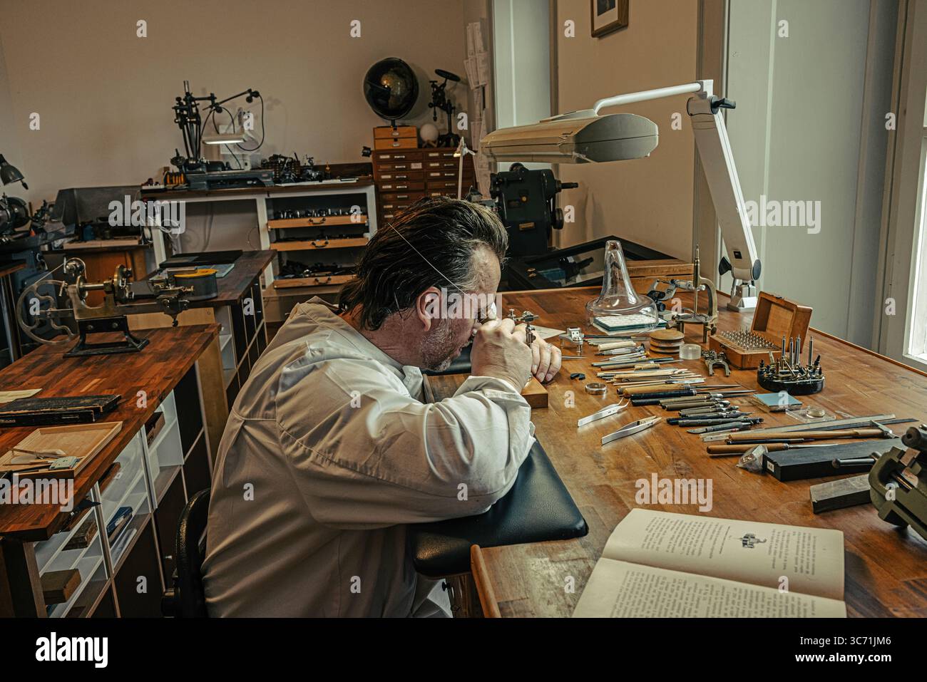 Hervé Schlüchter carefully regulating and cutting a hairspring in his watchmaking atelier, demonstrating the craftsmanship of Swiss horology. Stock Photo