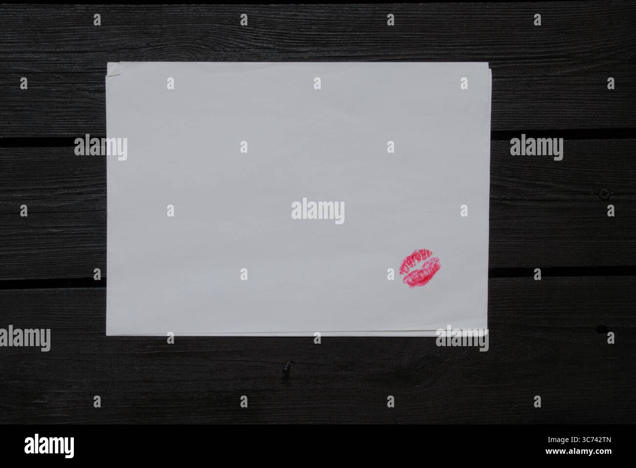 Bright lip imprint with red lipstick on white paper on wooden table ...