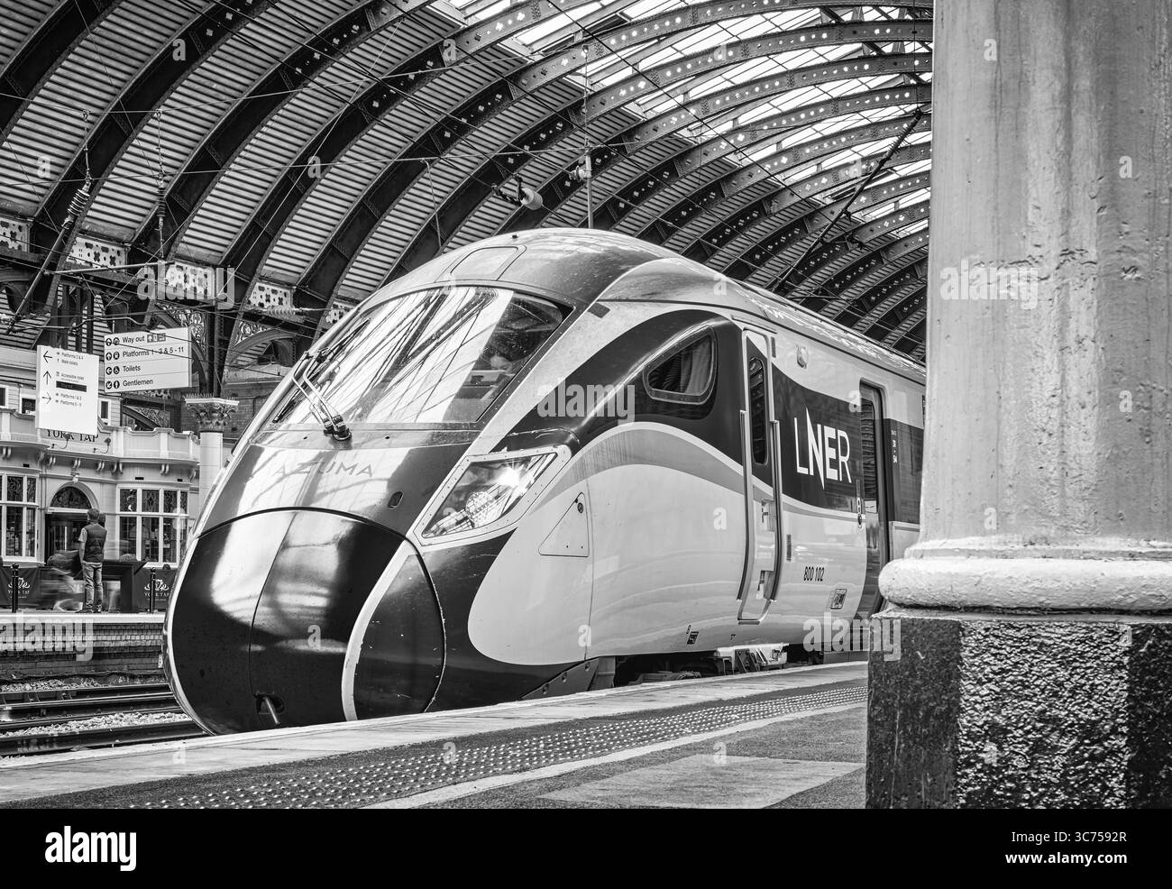 Train Columm A modern train stands at a historic railway station platform under a ...