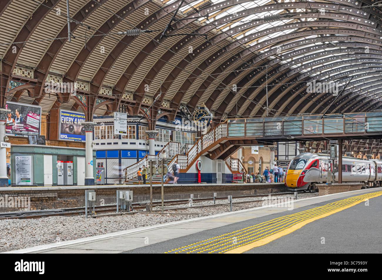 A railway station concourse under a 19th Century iron canopy. A ...