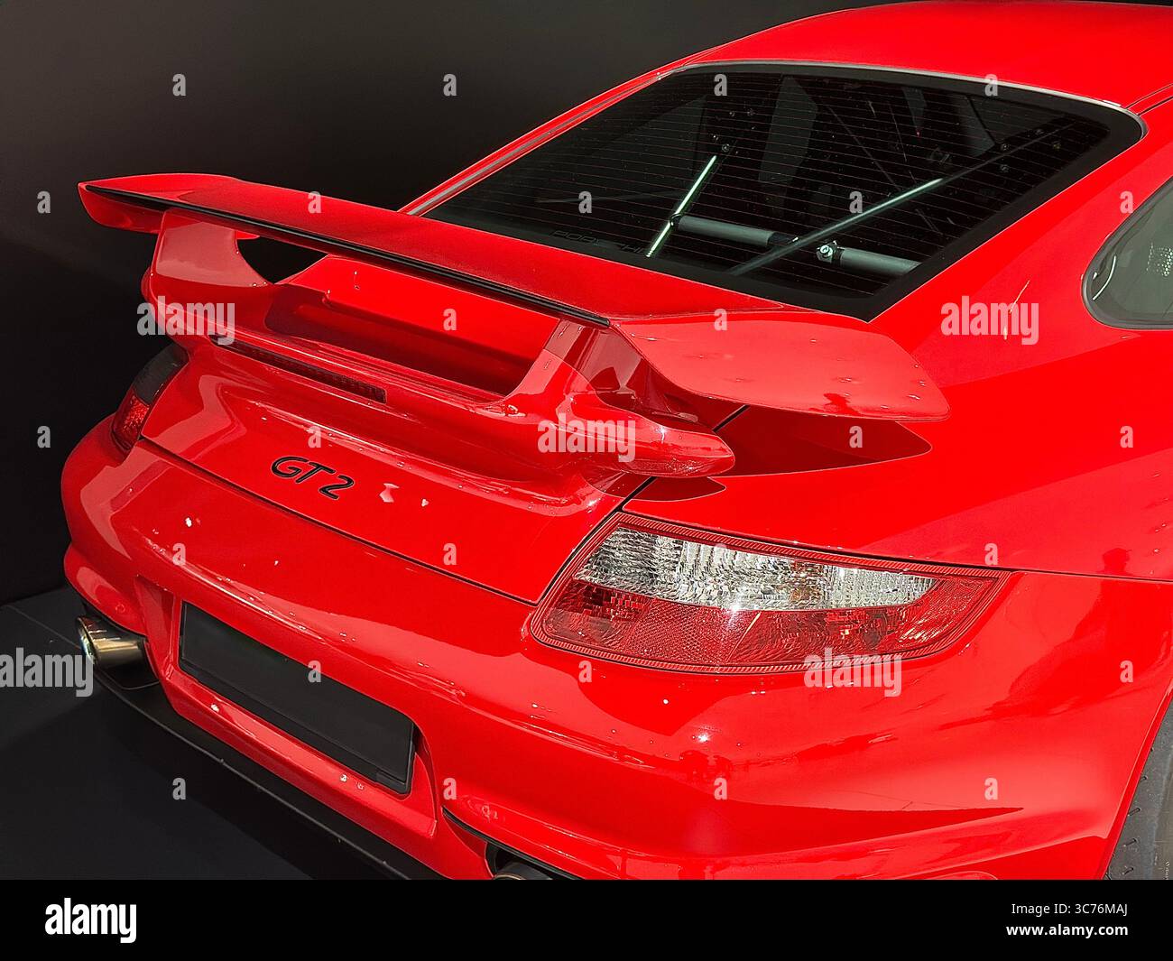 Rear view of a red Porsche 911 GT2 sports car, highlighting its large rear wing and taillights. Stock Photo