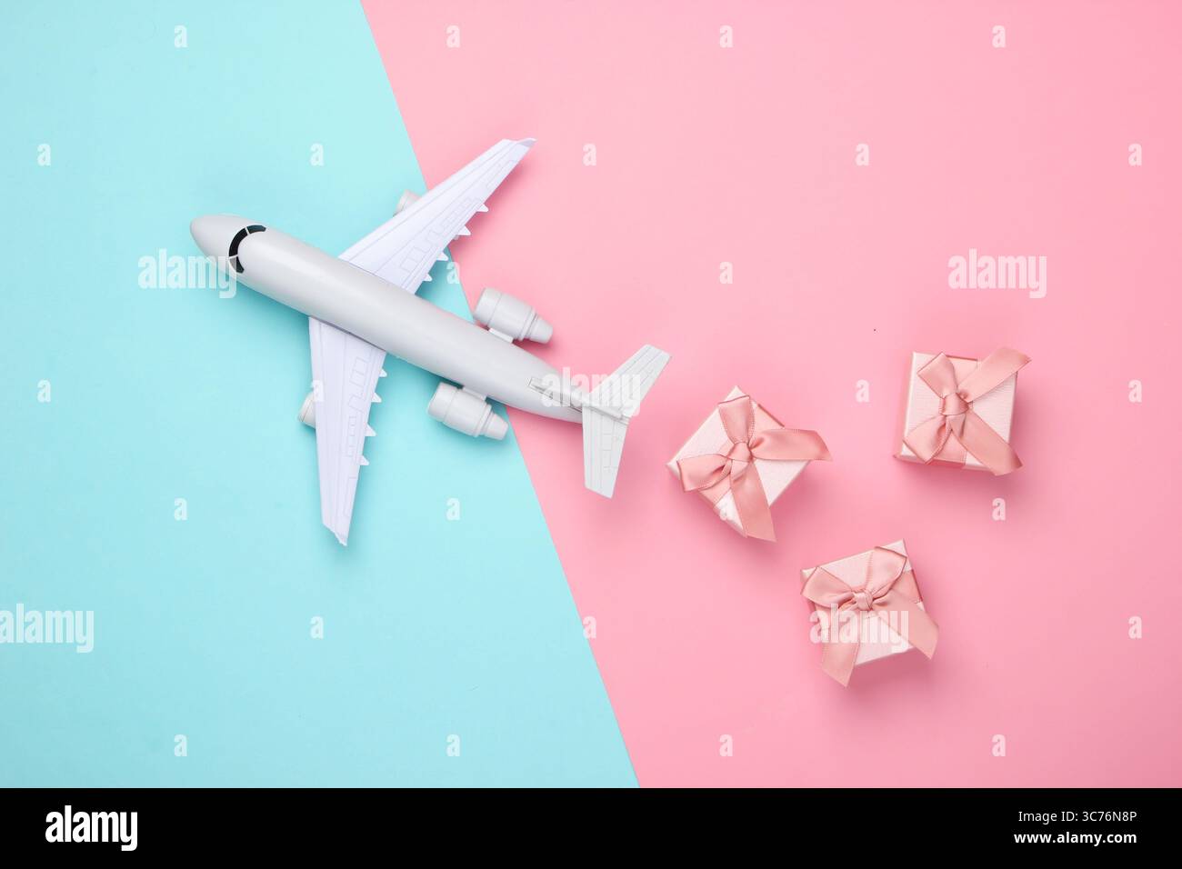 Air delivery. Plane figurine and gift boxes on pink blue pastel background. Flat lay. Top view Stock Photo