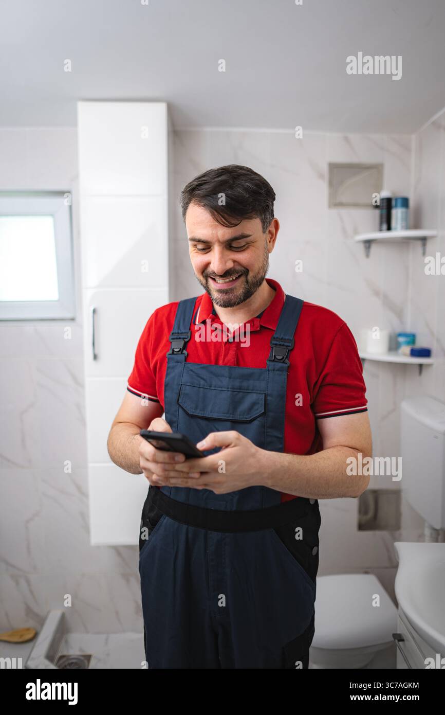 Plumber using smartphone in bathroom during house renovation Stock Photo