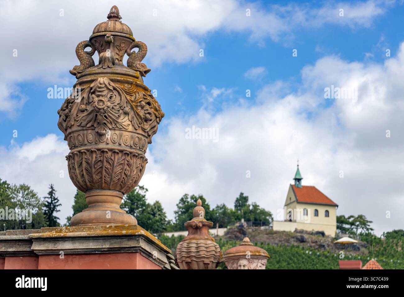 Ornamental stone vase and picturesque small church on hill against blue summer sky, Prague, Czechia Stock Photo