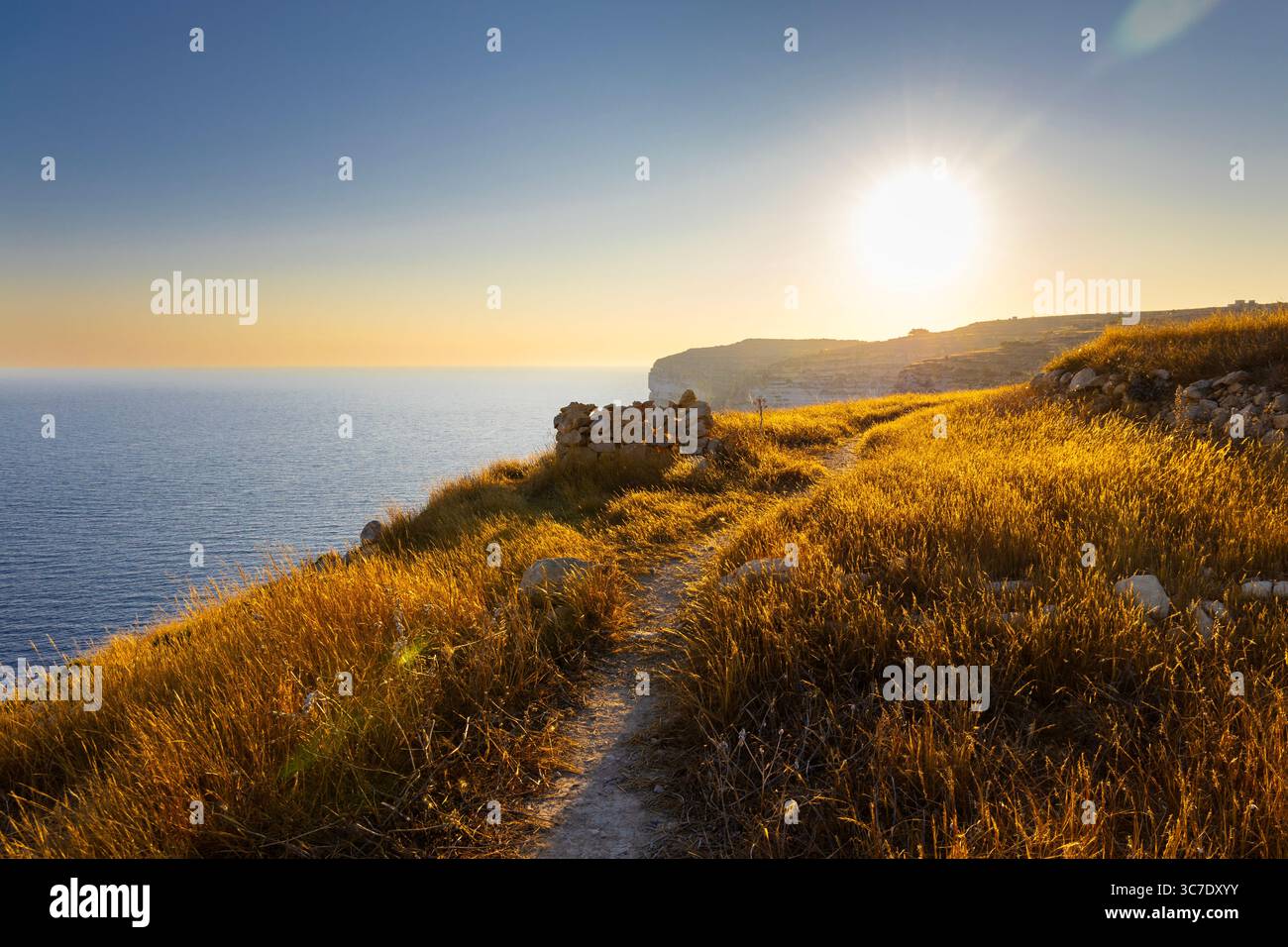 Coastal hiking path along the Xlendi cliffside at sunset, Gozo, Malta Stock Photo