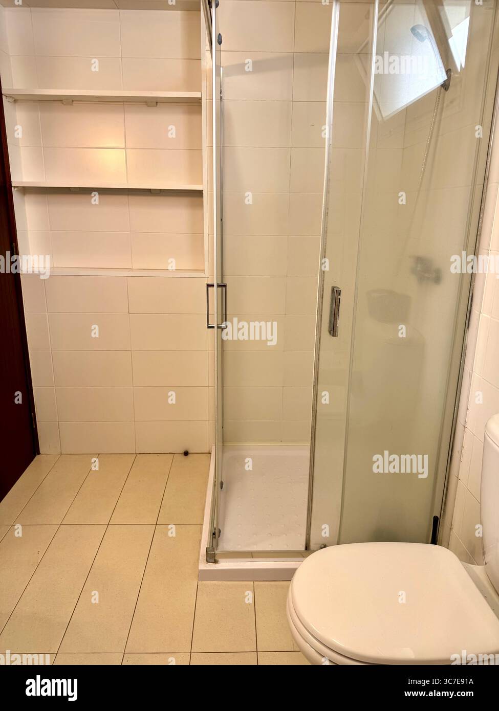 modern, clean bathroom with white tiles, a shower cabin, toilet, bidet, sink, and storage shelves. - Smartphone Captured Stock Image