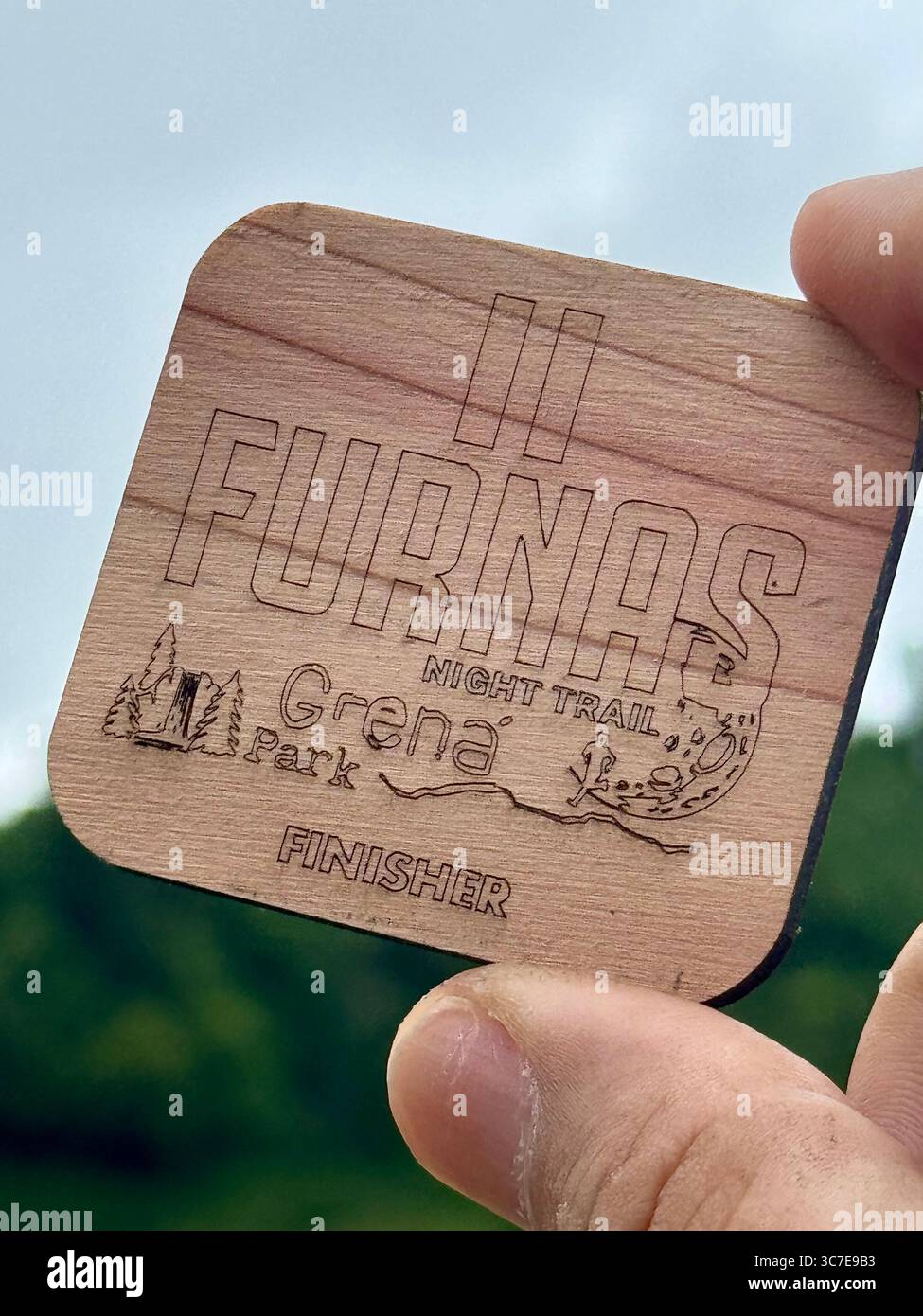 Wooden finisher medal from the Furnas Night Trail event held at Grená Park, São Miguel Island, Azores, Portugal. - Smartphone Captured Stock Image