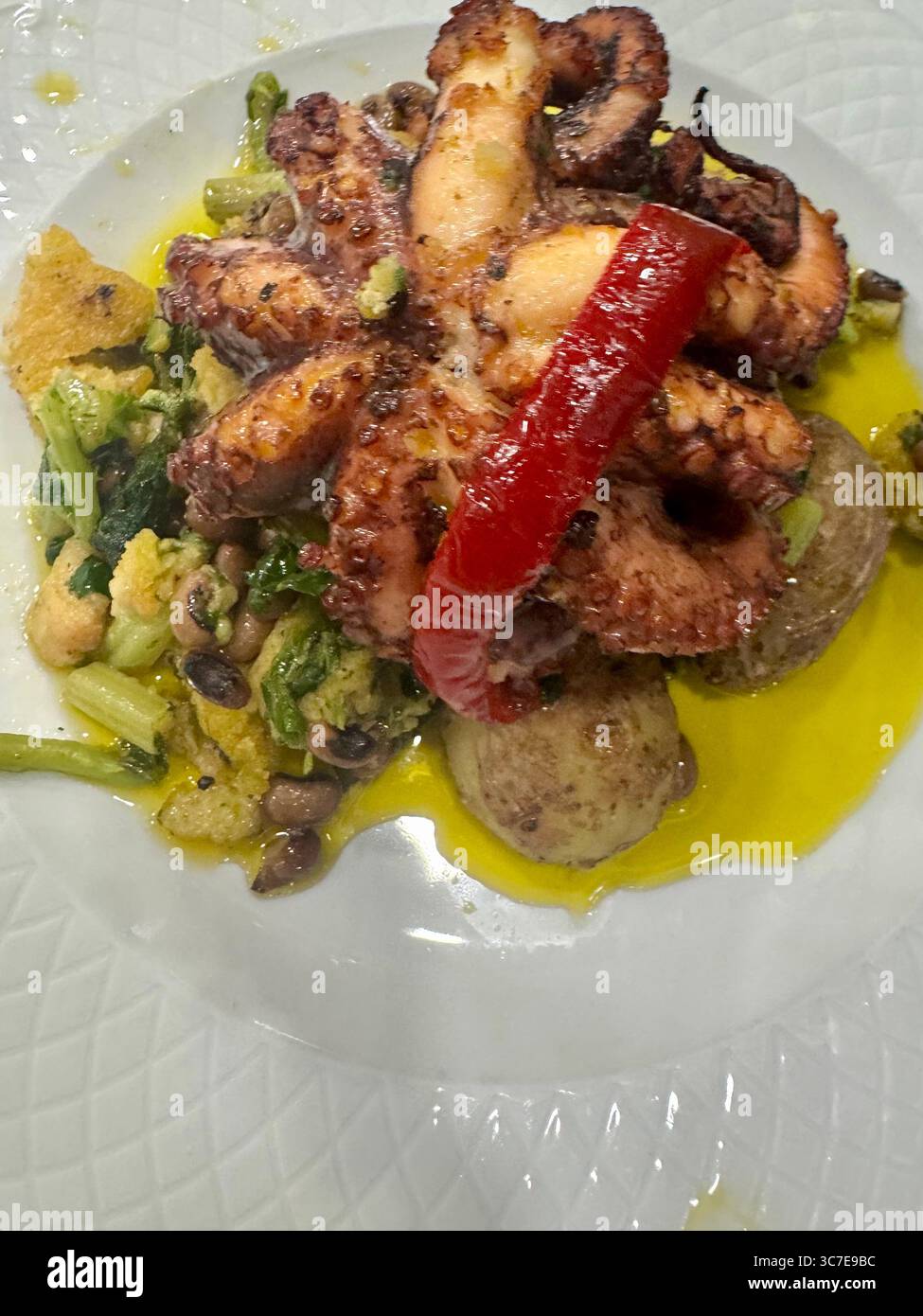 Traditional Portuguese octopus dish 'Polvo à Lagareiro' served with potatoes, vegetables, and olive oil. - Smartphone Captured Stock Image