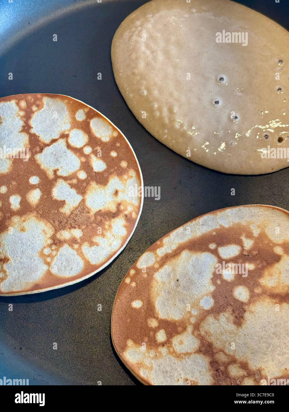 Homemade healthy banana oat egg protein pancakes cooking in a frying pan for a nutritious breakfast. - Smartphone Captured Stock Image