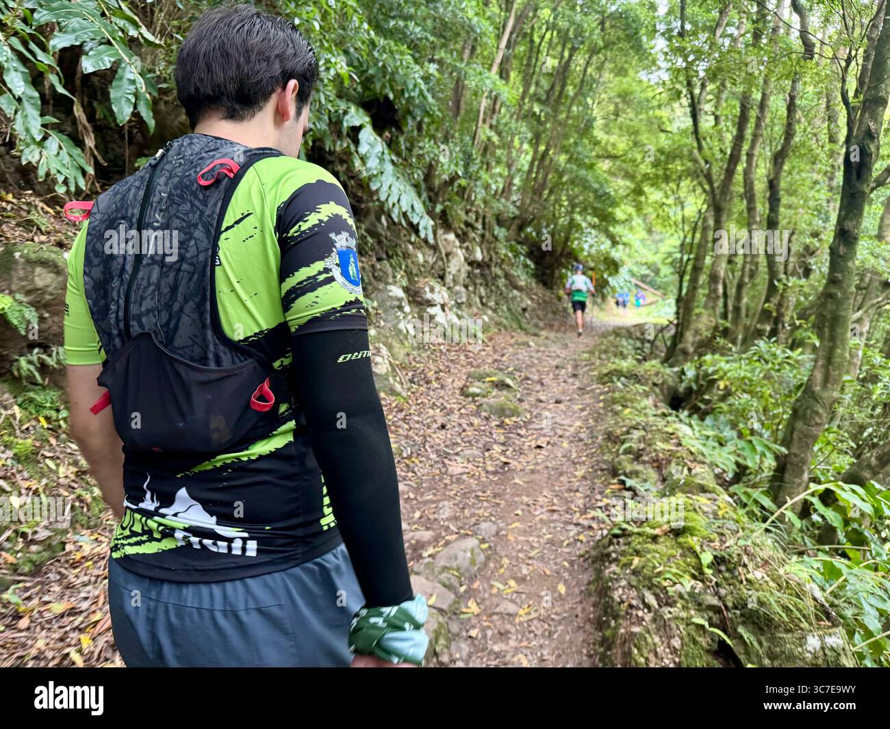 Participants running and hiking through lush forest trails and historic town streets during the Trail Real Priolo event in São Miguel Island, Azores, - Smartphone Captured Stock Image