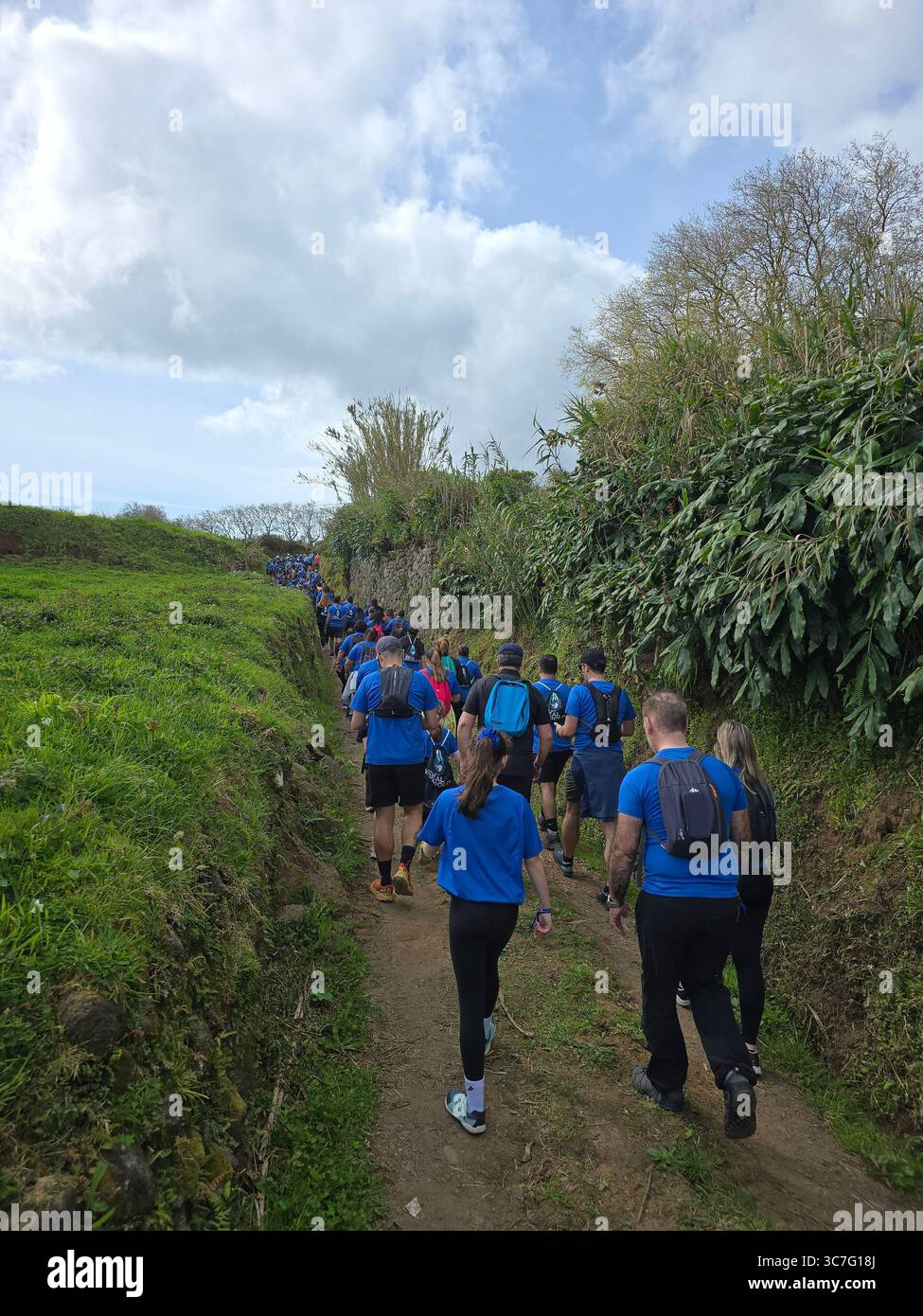 Participants running and hiking through lush forest trails and historic town streets during the Trail Real Priolo event in São Miguel Island, Azores, - Smartphone Captured Stock Image