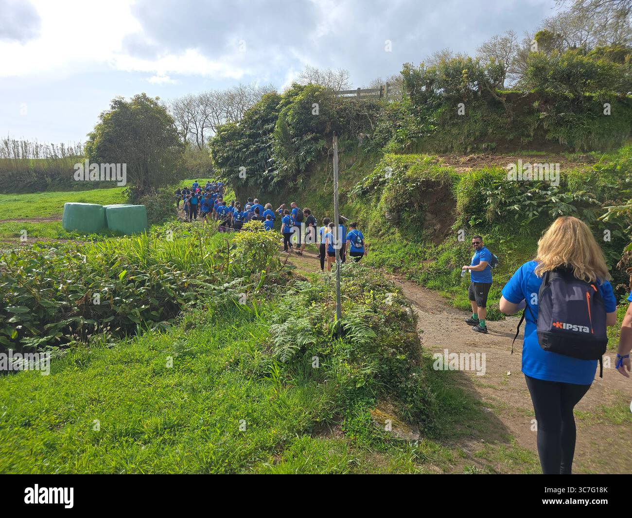 Participants running and hiking through lush forest trails and historic town streets during the Trail Real Priolo event in São Miguel Island, Azores, - Smartphone Captured Stock Image