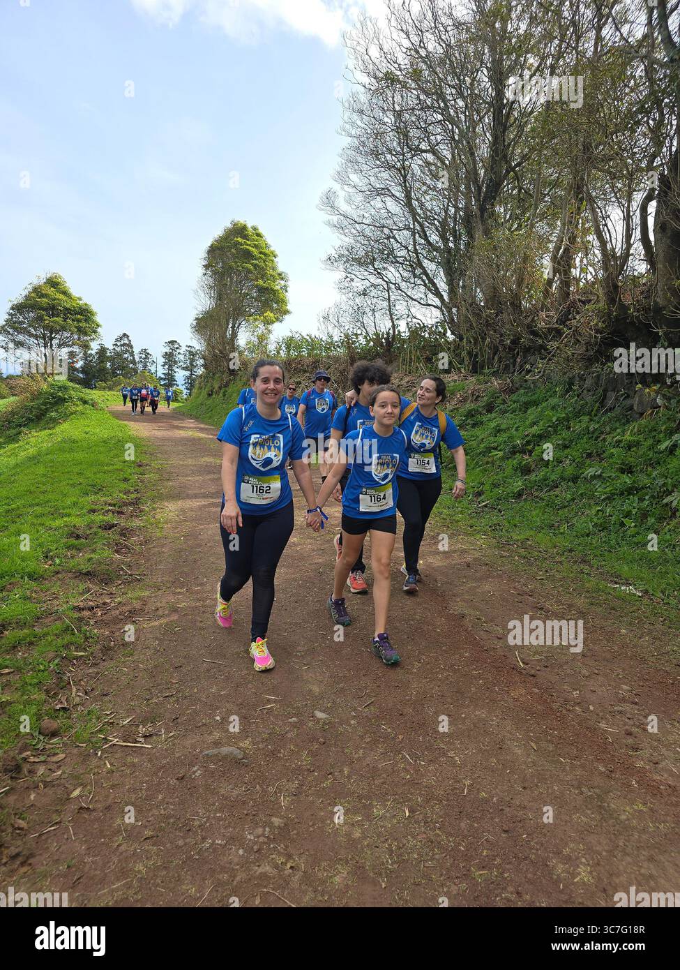 Participants running and hiking through lush forest trails and historic town streets during the Trail Real Priolo event in São Miguel Island, Azores, - Smartphone Captured Stock Image
