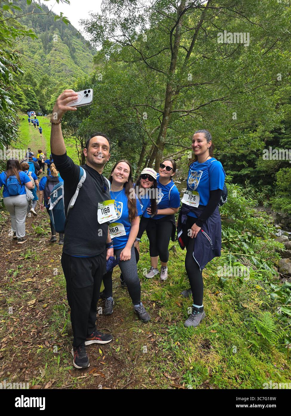 Participants running and hiking through lush forest trails and historic town streets during the Trail Real Priolo event in São Miguel Island, Azores, - Smartphone Captured Stock Image