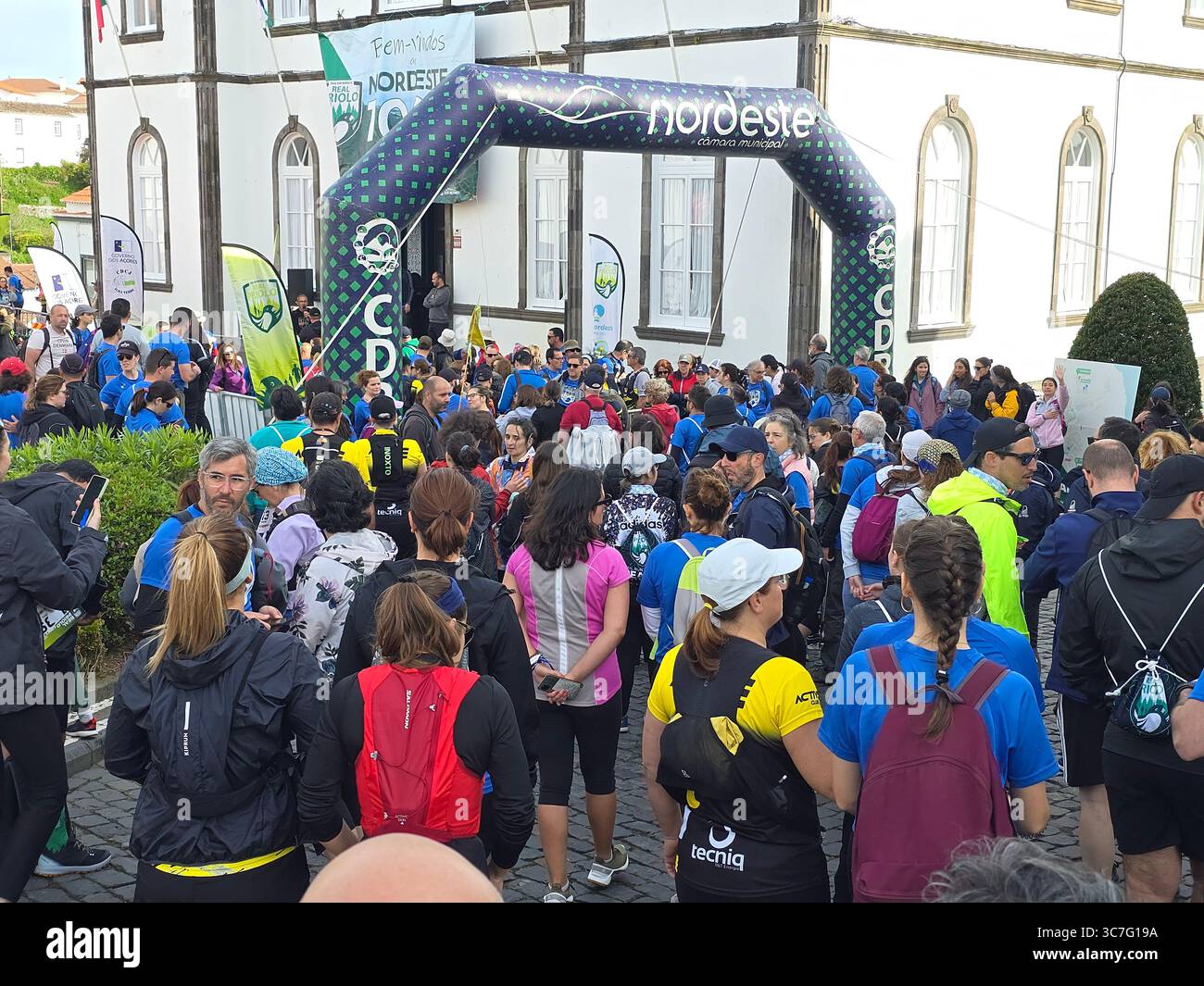 Participants running and hiking through lush forest trails and historic town streets during the Trail Real Priolo event in São Miguel Island, Azores, - Smartphone Captured Stock Image