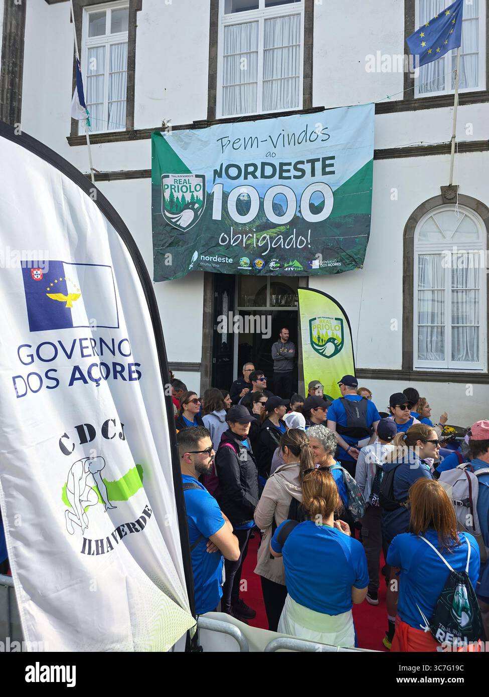 Participants running and hiking through lush forest trails and historic town streets during the Trail Real Priolo event in São Miguel Island, Azores, - Smartphone Captured Stock Image