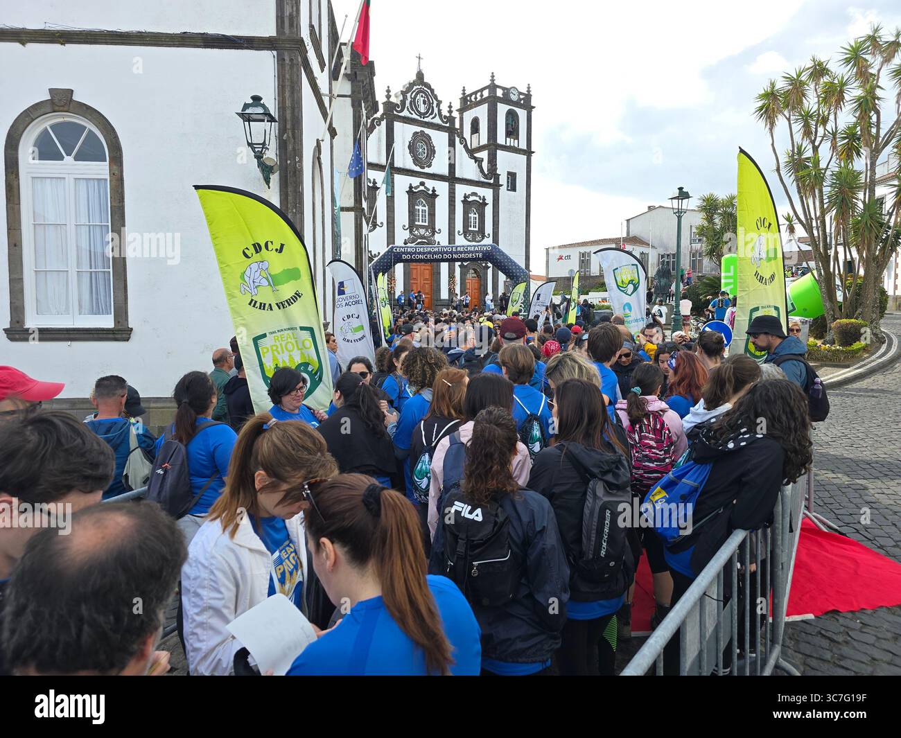 Participants running and hiking through lush forest trails and historic town streets during the Trail Real Priolo event in São Miguel Island, Azores, - Smartphone Captured Stock Image