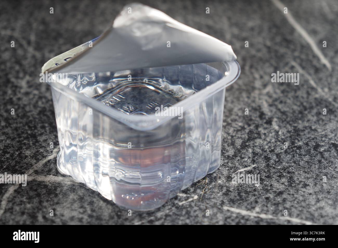 Clear plastic container filled with liquid on a surface Stock Photo - Alamy