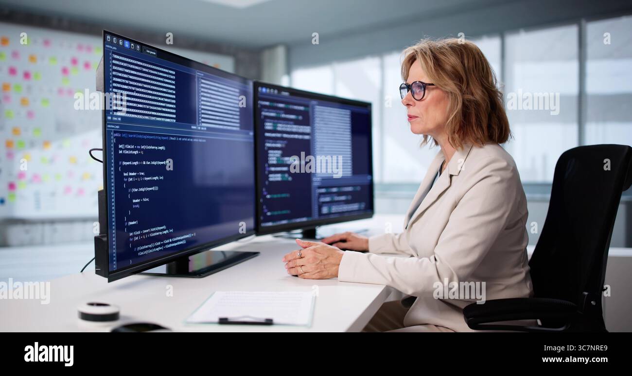 Senior Woman Coding Software On Desktop Screen As Remote Worker. Stock Photo