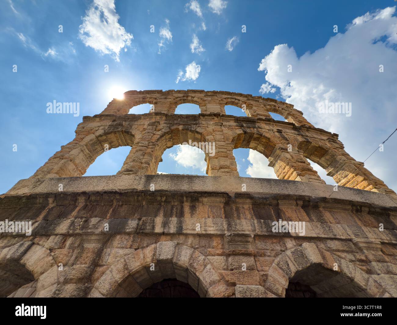 Verona Arena arches backlit by sun. Remains of Roman amphitheater against a blue sky in Verona, Italy - Smartphone Captured Stock Image