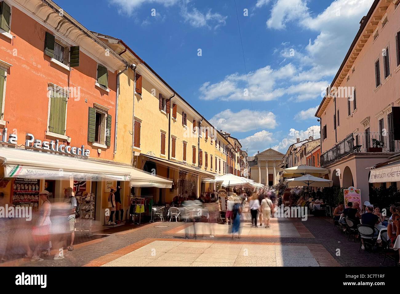 Pedestrianised street in town of Bardolino, Italy looking towards church of San Nicolò and San Severo, Piazza Giacomo Matteotti. Showing blurred touri - Smartphone Captured Stock Image