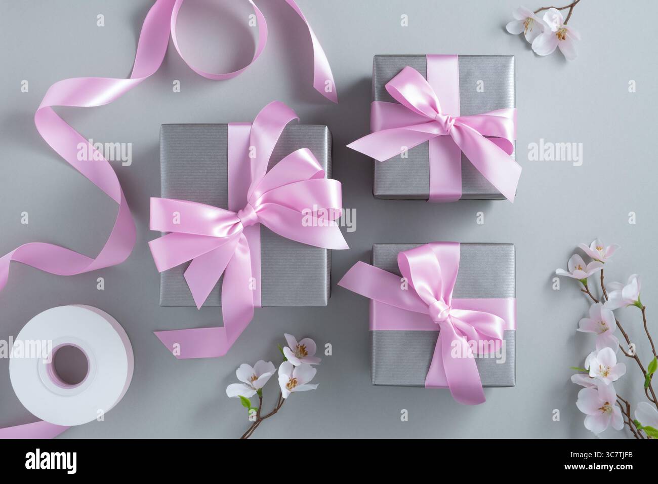 Silver gift boxes with pink bows on a gray background. Stock Photo