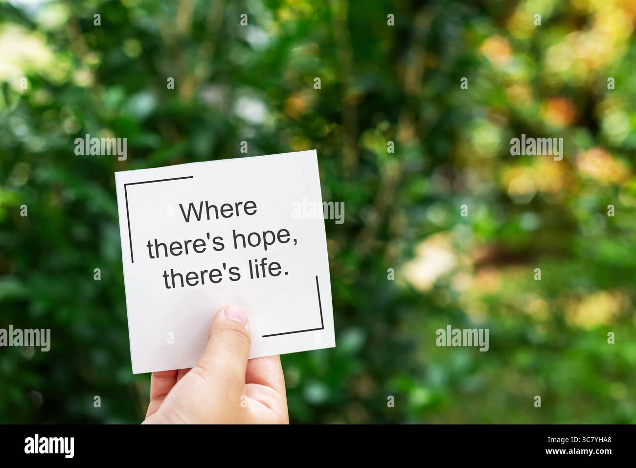 Hand holding torn paper with quotes where there's hope, there's life Stock Photo