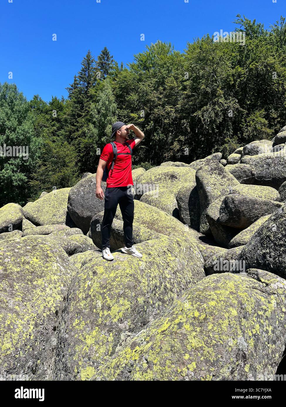 Male hiker standing on large boulder at the Golden Bridges stone river in Vitosha Mountain, Sofia Bulgaria, Southeastern Europe, Balkans, EU Stock Photo
