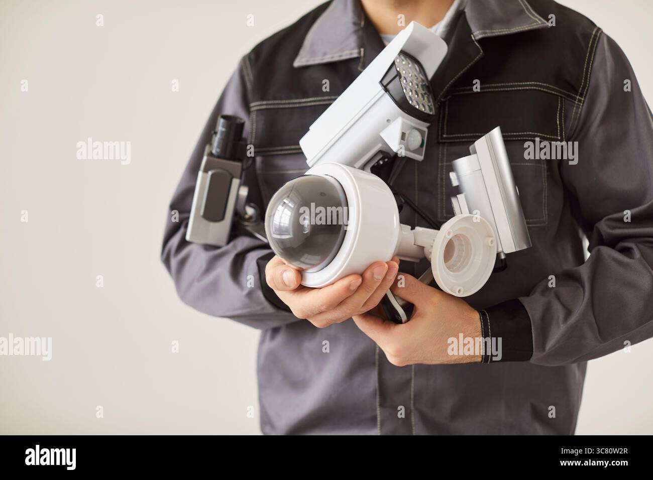 Unrecognizable male technician in uniform holding cctv security camera and going to install it Stock Photo