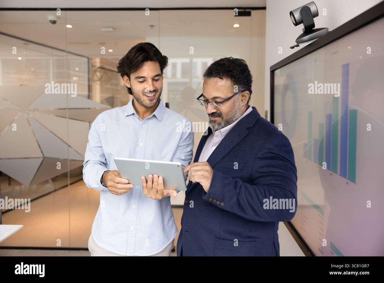 Young worker explain successful solution to smiling leader using tablet Stock Photo