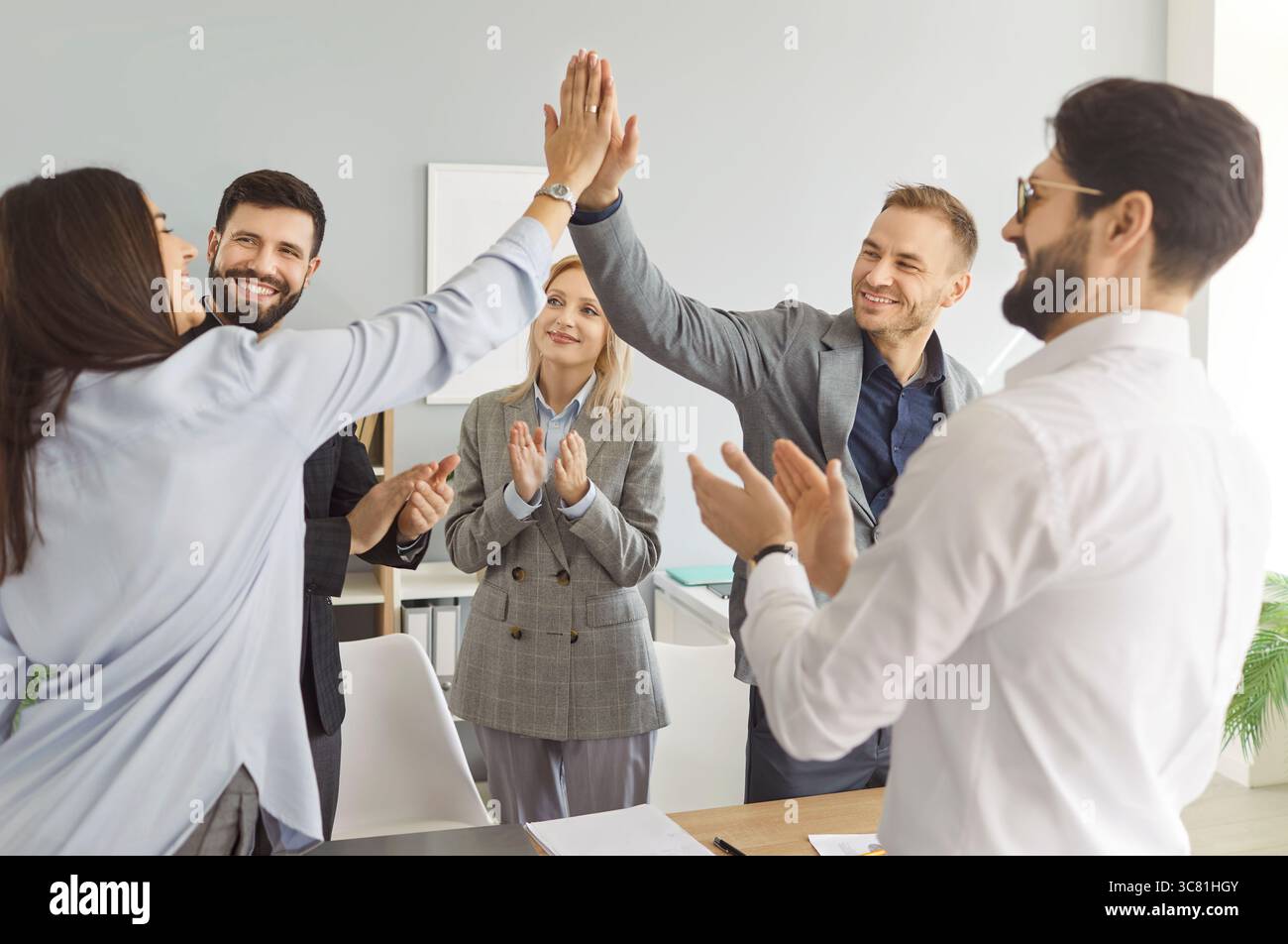 Happy friendly diverse employees common high five congratulating with business achievement Stock Photo